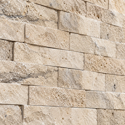 Close-up of classic travertine split face stone showing natural colour variation, pores and a textured surface.