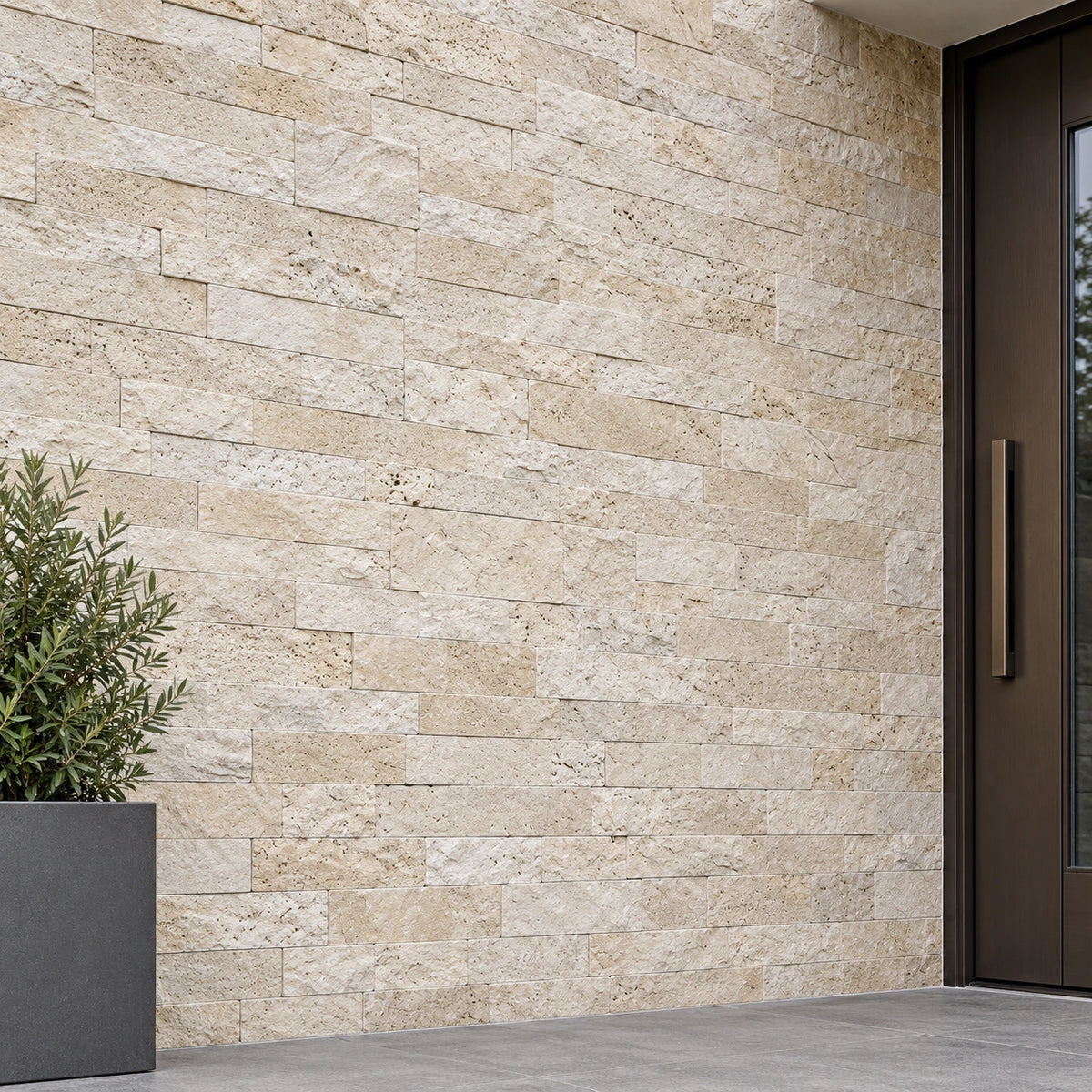 Light travertine split face wall cladding beside a dark entrance door and planter in an exterior visualisation.