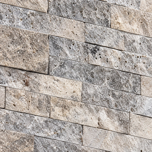 Close-up of silver travertine split face stone showing natural colour variation, pores and a textured surface.