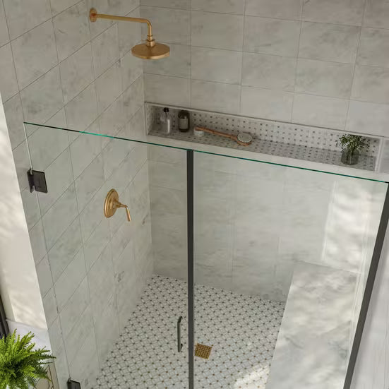 Modern shower with glass enclosure, gold fixtures, and tiled walls.