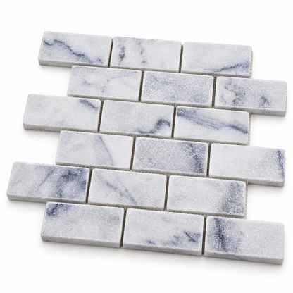 Carrara White Tumbled Marble Brick Mosaic Tile 50x100 — angled sheet showing 10 mm natural marble edges and mesh backing
