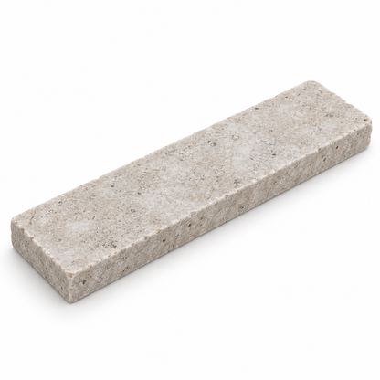 Angled view of a Dijon tumbled limestone 50 x 200 x 15 mm tile showing its worn edge and natural stone texture.