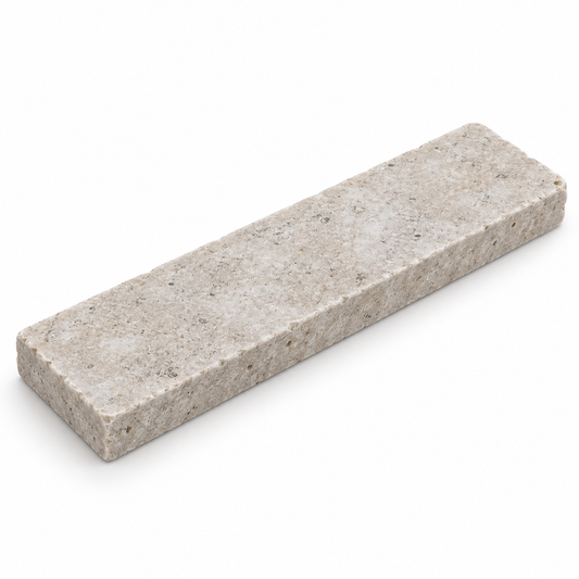 Angled view of a Dijon tumbled limestone 50 x 200 x 15 mm tile showing its worn edge and natural stone texture.