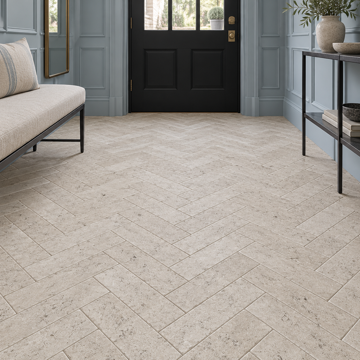 Dijon tumbled limestone herringbone flooring in an entrance hall with pale blue panelling and a black front door.