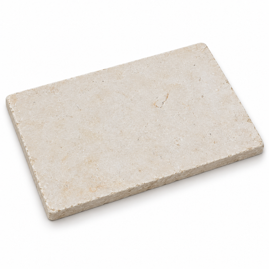 Angled view of a Galala Ivory tumbled limestone 600 x 400 x 15 mm tile with rounded corners and a gently worn stone edge.