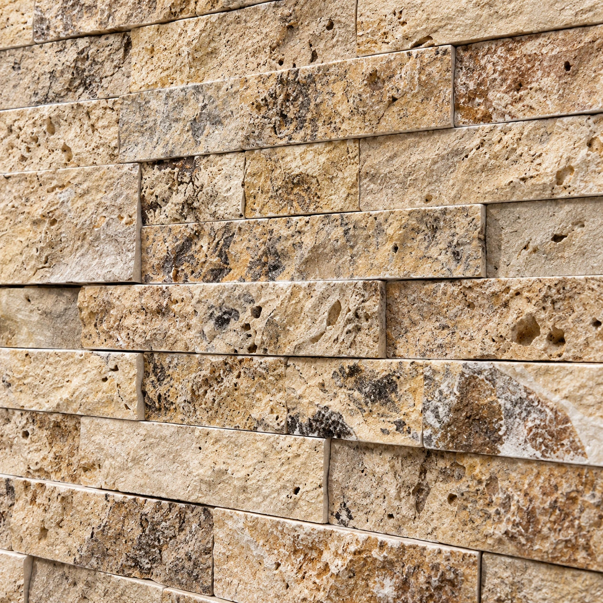 Close-up of scabos travertine split face stone showing natural colour variation, pores and a textured surface.