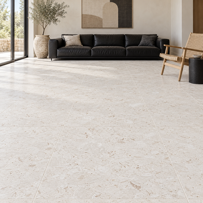 Shellstone brushed limestone 610 x 610 mm square floor tiles in a living room with a black leather sofa.