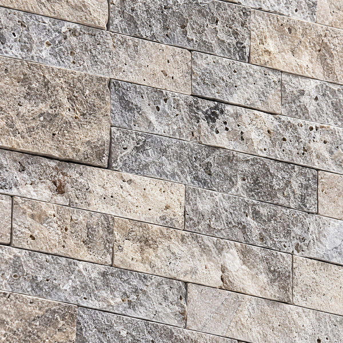Close-up of silver travertine split face stone showing natural colour variation, pores and a textured surface.